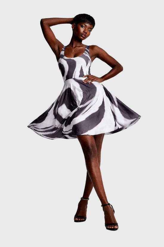 Woman wearing a charcoal and white patterned dress on a plain background