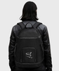 Person wearing a black backpack with a logo on a gray background