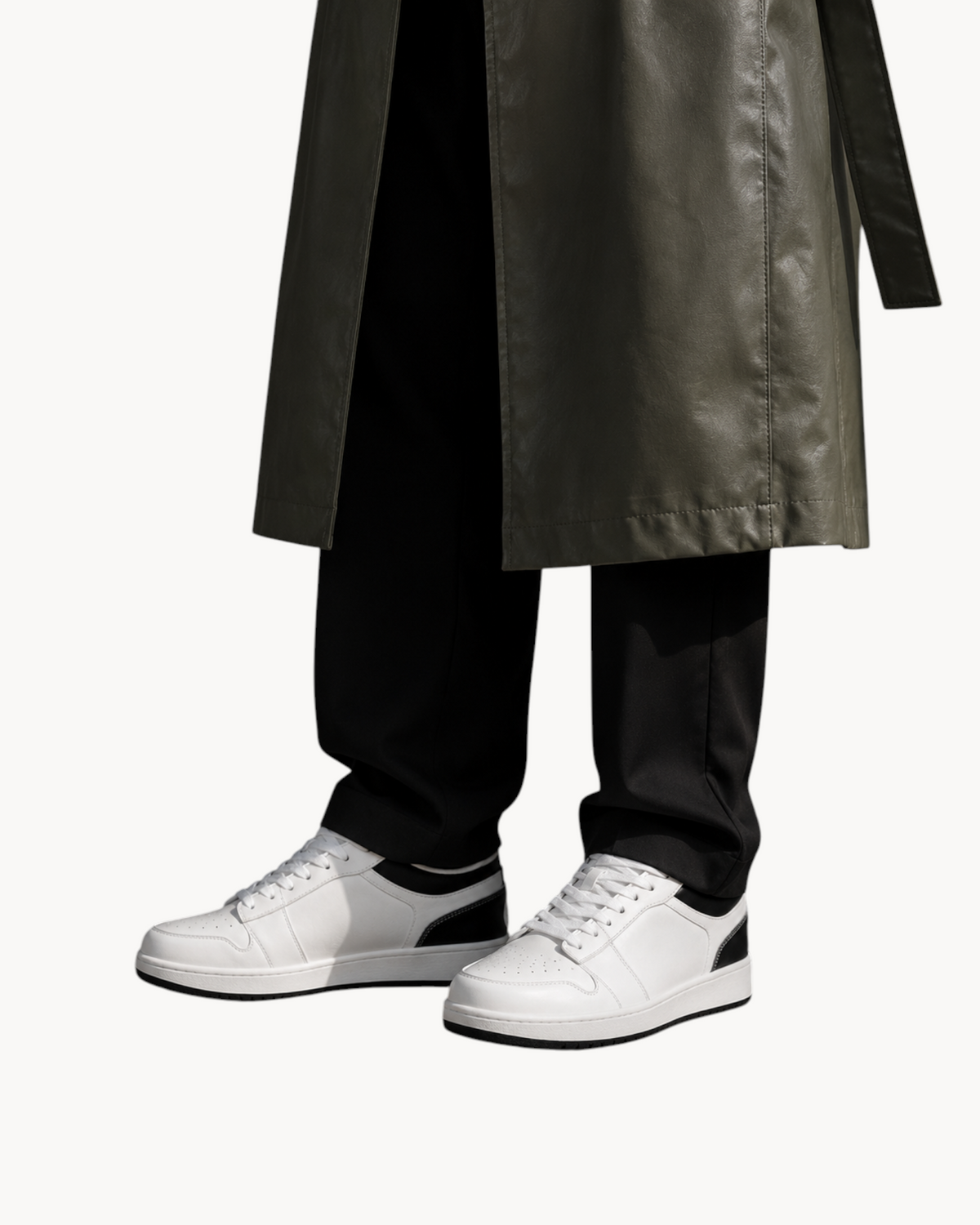 Sailuc Low Form sneakers in white technical PU with black accents, worn with dark trousers and a long coat.