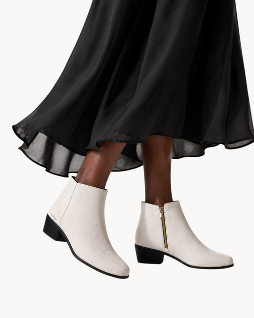 Sailuc ankle boots in off-white technical suede with a matte finish, side zipper, and low block heel worn with a skirt